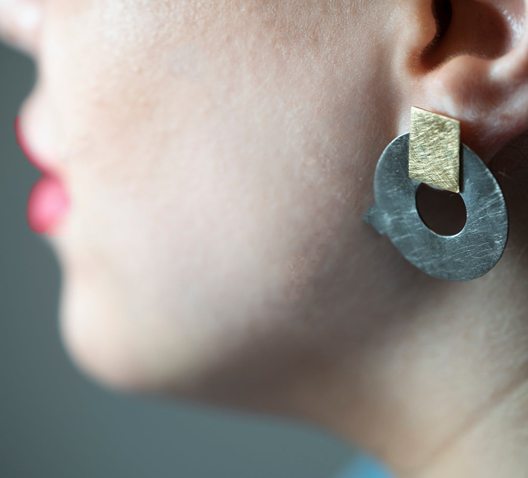 18K Gold earring holding a Titanium ring