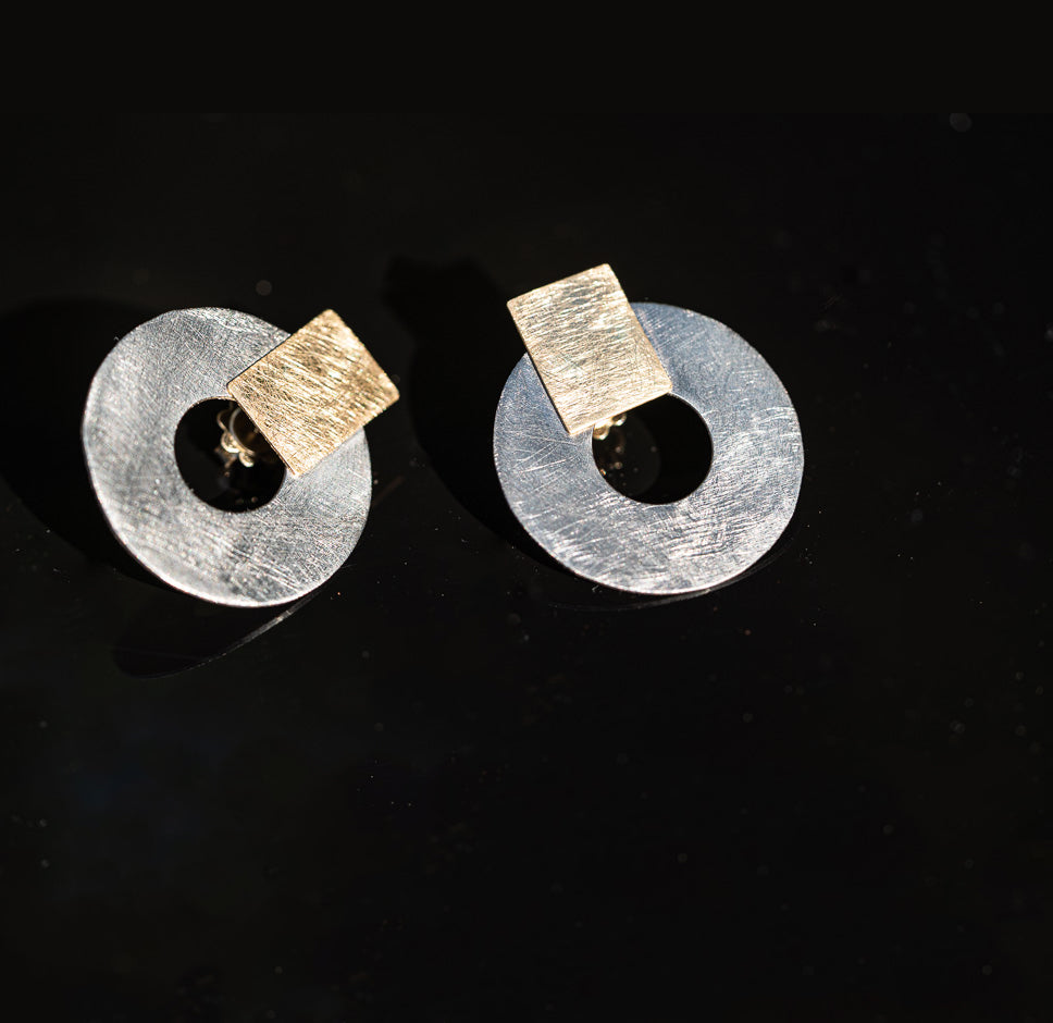 18K Gold earring holding a Titanium ring